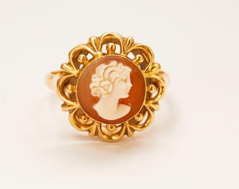 Op de afbeelding: Een gouden ring met een cameo van een vrouwenprofiel. De cameo is gezet in een gouden frame met een bloemmotief.