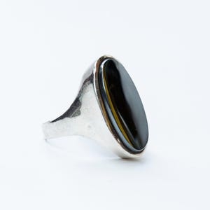 May include: A silver ring with a black oval gemstone set in a bezel setting.