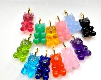 May include: Assortment of gummy bear charms in various colours, including red, green, yellow, blue, purple, pink, black, and clear. Each charm features a gold loop for attaching to jewellery or other crafts.