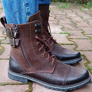 Close-up of the sleek metal side zipper on genuine leather ankle boots, highlighting fine craftsmanship and practical design.