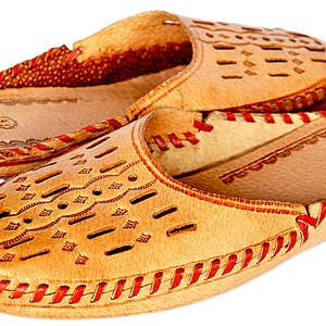 May include: A pair of tan leather slippers with red stitching and a decorative cut-out pattern. The slippers have a closed toe and a slip-on design.