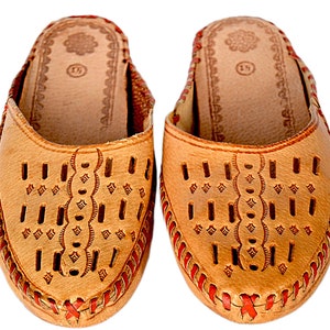 May include: A pair of tan leather slippers with red stitching and a decorative pattern. The slippers have a pointed toe and an open back.