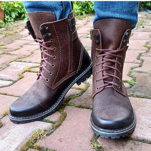May include: Brown leather boots with laces and a side zip. The boots have a rugged sole and a pointed toe.