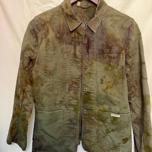 May include: A green utility jacket with a tie-dye pattern. The jacket has a button-up front, two chest pockets, and two large front pockets. The jacket has a small patch on the bottom right pocket that says "Patagonia".