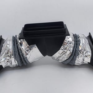 May include: Black plastic HVAC duct with a rectangular top and accordion-style flexible tubing. The tubing is lined with silver foil. The duct has a curved shape and is designed for air ventilation systems.