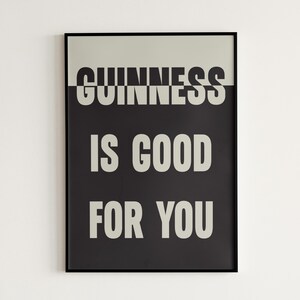 May include: A framed poster with the words "GUINNESS IS GOOD FOR YOU" in white, bold font against a black and light gray background. The poster is rectangular and has a black frame.