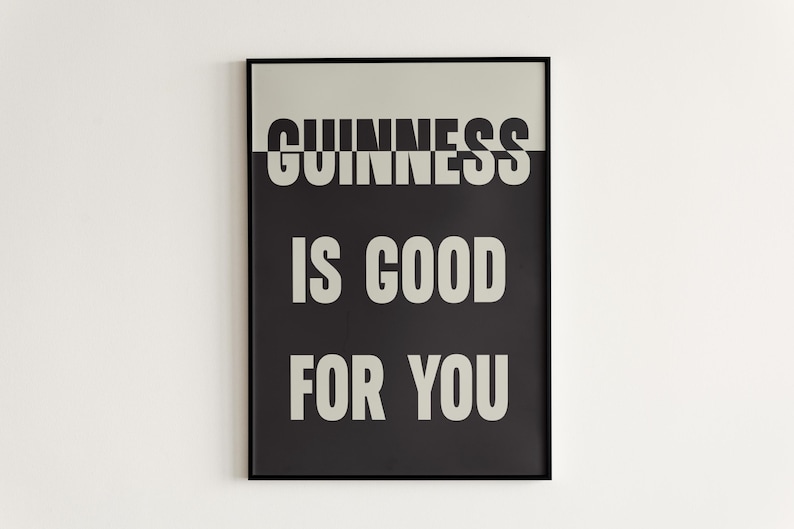 May include: A framed poster with the words "GUINNESS IS GOOD FOR YOU" in white, bold font against a black and light gray background. The poster is rectangular and has a black frame.