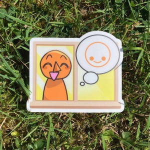 Pu&ograve; includere: Un adesivo raffigurante un personaggio dei cartoni animati con corpo e viso arancione, sorridente e che guarda fuori da una finestra. Una nuvoletta mostra una faccia sorridente. Lo sfondo &egrave; giallo.