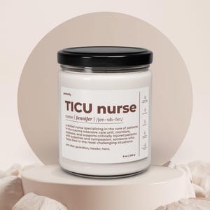 Peut inclure: Bougie blanche dans un bocal en verre avec un couvercle noir. L'étiquette indique "TICU nurse" avec le nom "Jennifer" et une définition. La bougie est de 255 g. La bougie est sur un piédestal blanc.