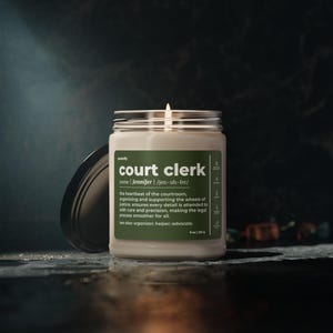 May include: A beige candle with a green label that reads "court clerk" and a definition of the term. The candle is lit and the flame is visible.