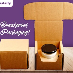 May include: Two brown cardboard boxes, one open and one closed. The open box has a black lidded jar inside. The closed box is on a wooden surface. The text "Breakproof Packaging!" is printed on the background.
