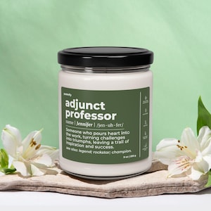 Puede incluir: Un tarro de vela blanco con una etiqueta verde que dice "profesor adjunto" con el nombre "Jennifer" y la pronunciación fonética. La etiqueta también incluye la definición: "Alguien que pone el corazón en el trabajo, convirtiendo los desafíos en triunfos, dejando un rastro de inspiración y éxito." El tarro de vela está sentado sobre una superficie de madera con flores blancas.