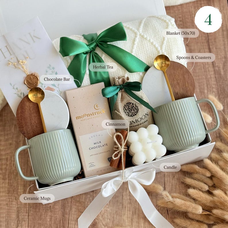 May include: A gift box with a white ribbon, containing a blanket, mugs, chocolate, herbal tea, cinnamon, and a candle. The box includes a ceramic mug, a chocolate bar, and a small bag of cinnamon. The blanket measures 50x70 inches.