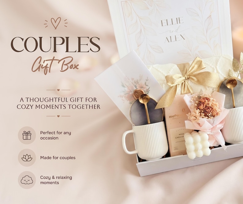 May include: A couples gift box with a white mug, gold spoon, chocolate bar, and small bouquet. The box includes a card and a candle. The box is white with the words "Couples Gift Box" on the front.