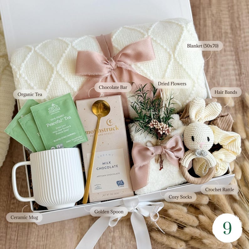 Pu&ograve; includere: Una confezione regalo piena di una coperta bianca (127x178 cm), t&egrave; biologico, una tazza di ceramica, una barretta di cioccolato, fiori secchi, un cucchiaio dorato, elastici per capelli, calzini accoglienti e un sonaglio all'uncinetto. La scatola &egrave; legata con un nastro rosa.