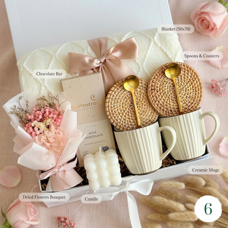 Pu&ograve; includere: Una confezione regalo con una coperta bianca (50x70 cm), due tazze in ceramica, una barretta di cioccolato, un bouquet di fiori secchi, una candela, due cucchiai e due sottobicchieri. La scatola &egrave; legata con un nastro rosa.