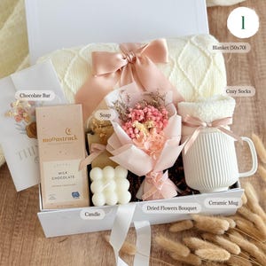 Cozy gift set for women with chocolate bar, fluffy socks, soap, 
dried flowers, candle, and ceramic mug — romantic gift box for her