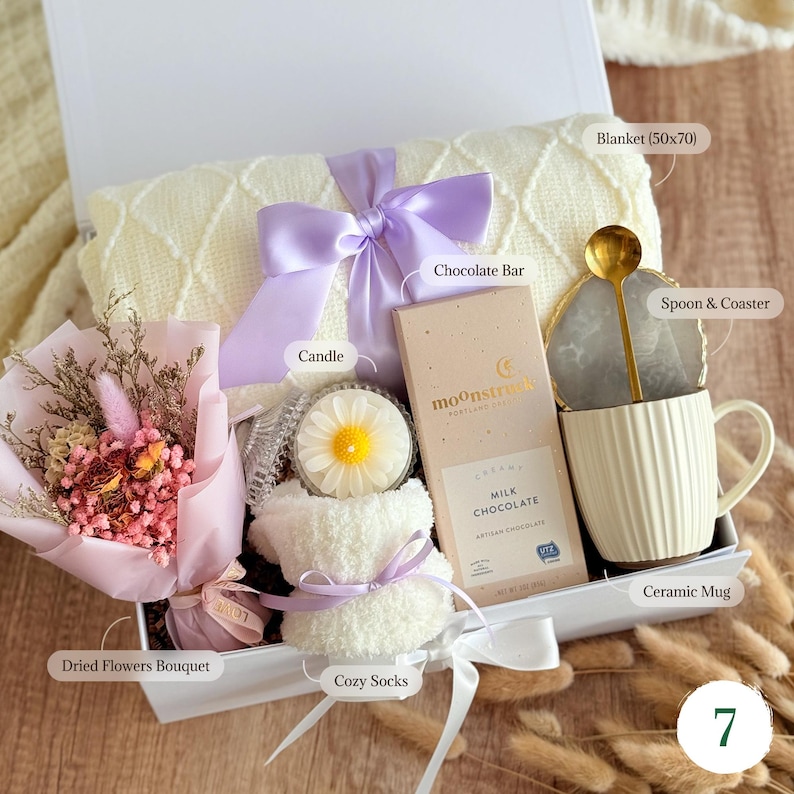 Cozy gift basket with soft blanket, dried flower bouquet, fluffy socks, 
ceramic mug, and chocolate — care package gift for her