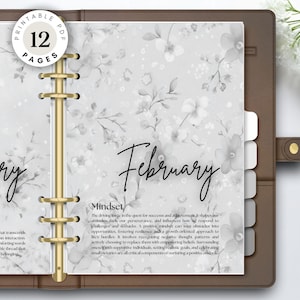 Op de afbeelding: Een planner met een bloemenpatroon, met de maanden januari en februari. De planner heeft een bruine kaft en gouden ringen. De tekst "PRINTABLE PDF 12 PAGES" is zichtbaar. De planner is ontworpen om te helpen met mindset en doelen.