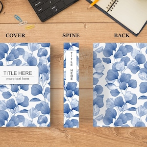 May include: A book cover with a blue and white floral pattern. The title "TITLE HERE" is printed on the front cover with the text "more text here" below it. The spine of the book has the title "TITLE HERE" printed vertically. The back cover has the same floral pattern as the front cover.
