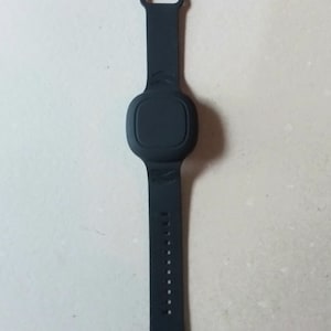 May include: A black wristband with a round, black button on the front. The wristband has a silver buckle.