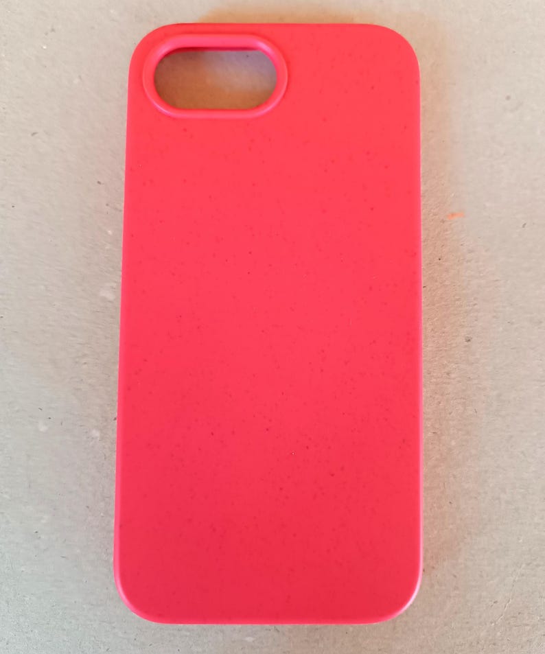 May include: A bright red phone case with a rectangular shape and a camera opening at the top. The case is made of a smooth material and is designed to protect a smartphone.