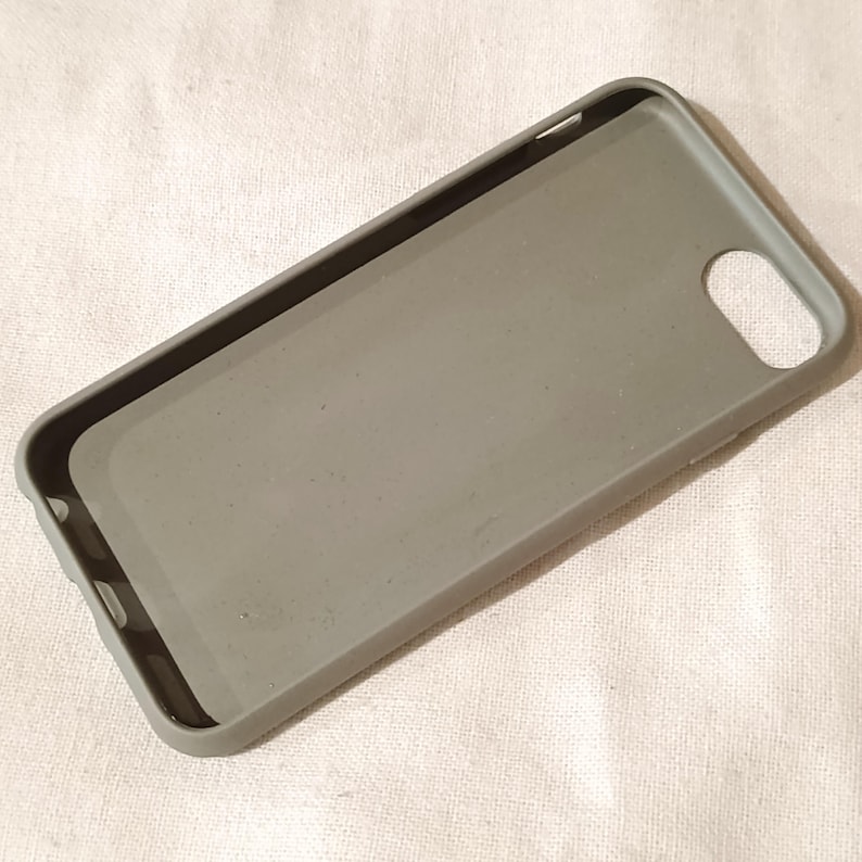 Peut inclure: Une coque de t&eacute;l&eacute;phone grise avec une finition mate. La coque a une forme rectangulaire avec des coins arrondis et un trou pour l'appareil photo. L'int&eacute;rieur est d'une nuance de gris plus claire. La coque est con&ccedil;ue pour prot&eacute;ger un t&eacute;l&eacute;phone.