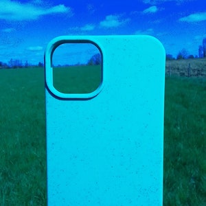 Op de afbeelding: Een lichtblauwe telefoonhoes met een uitsparing voor de camera lens. De hoes is gemaakt van een getextureerd materiaal en heeft een gespikkelde uitstraling.