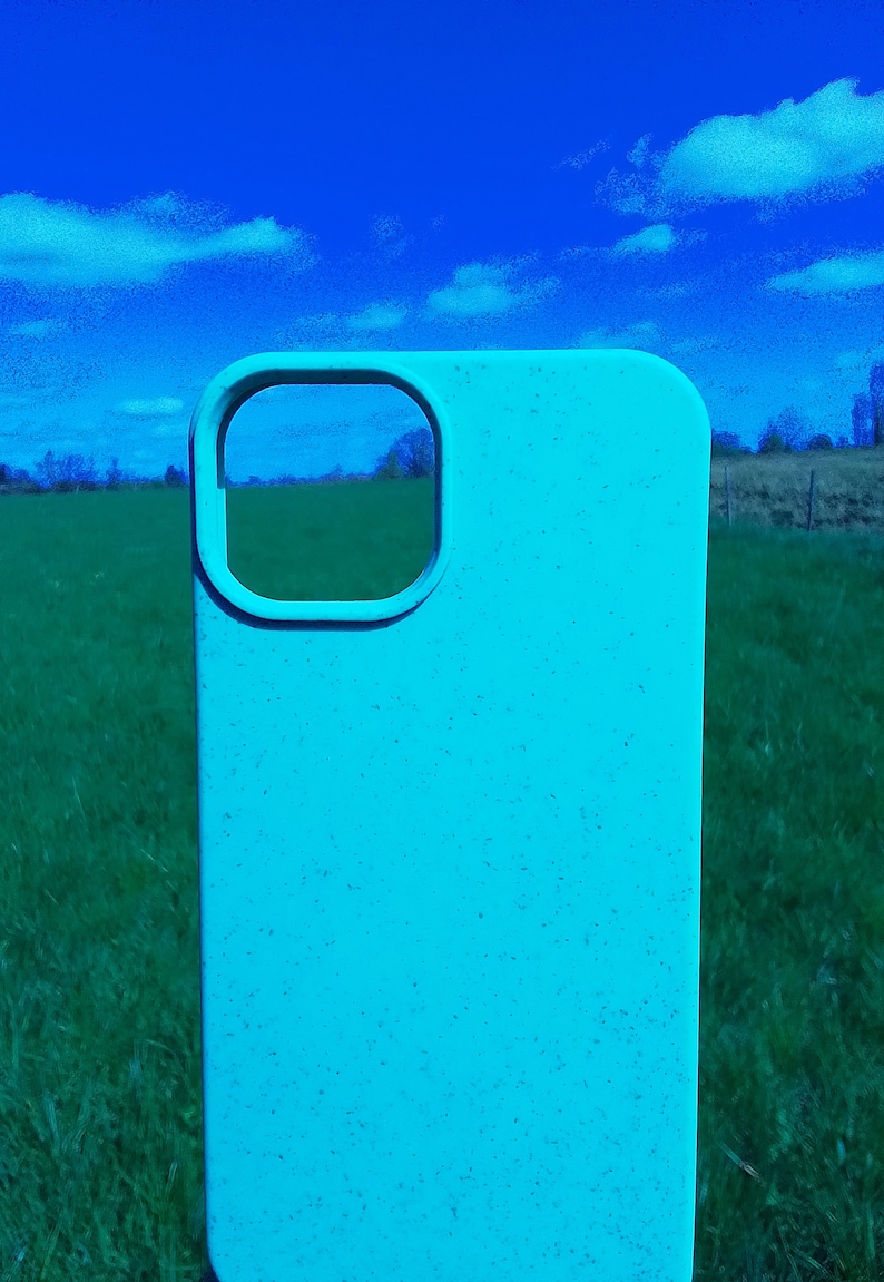 Op de afbeelding: Een lichtblauwe telefoonhoes met een uitsparing voor de camera lens. De hoes is gemaakt van een getextureerd materiaal en heeft een gespikkelde uitstraling.