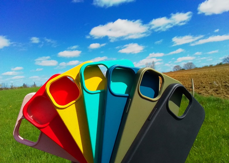 Op de afbeelding: Een set van zeven kleurrijke telefoonhoesjes in roze, rood, geel, turquoise, blauw, groen en zwart. De hoesjes zijn gemaakt van siliconen en hebben een verhoogde camerabult.