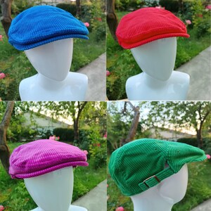 Könnte beinhalten: Vier verschiedene Cord-Newsboy-Mützen in verschiedenen Farben. Die Mützen werden auf Mannequins mit der Mütze nach vorne präsentiert. Die Mützen sind blau, rot, pink und grün.