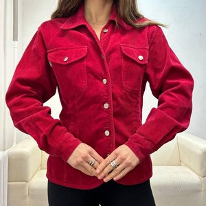Puede incluir: Una camisa de pana roja con botones, mangas largas y dos bolsillos de solapa. La camisa es entallada y tiene un cuello cl&aacute;sico.