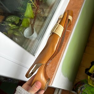 K&ouml;nnte beinhalten: Braune Slingback-Heels aus Leder mit beigem Riemen und Schnalle. Die Schuhe haben einen kleinen Absatz und eine spitze Zehenpartie. Die Schuhe liegen auf einer Fensterbank. Absatzh&ouml;he ca. 5 cm.