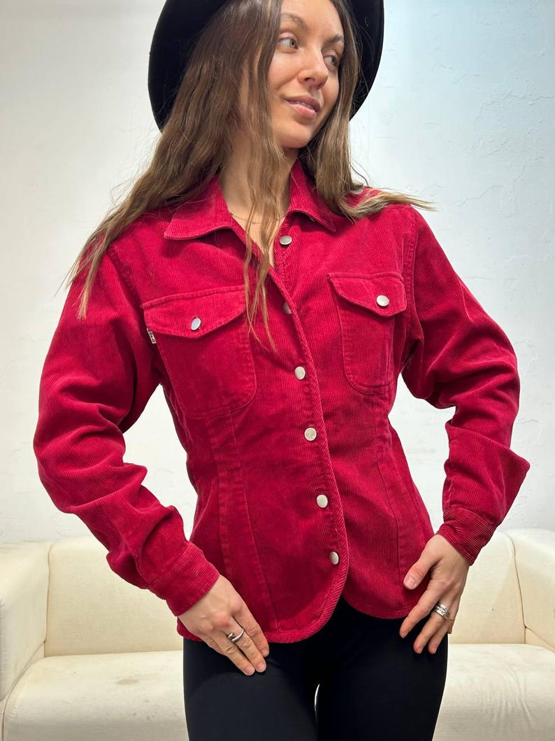 Puede incluir: Una camisa de pana roja con botones, mangas largas y dos bolsillos en el pecho.