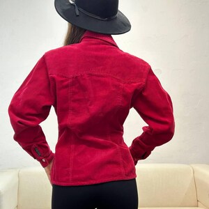 Puede incluir: Una camisa de pana roja de manga larga y cierre de botones. La camisa es entallada y tiene cuello.