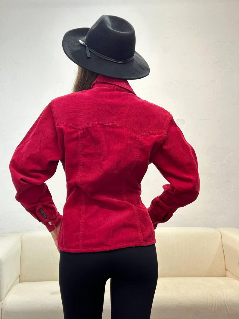 Puede incluir: Una camisa de pana roja de manga larga y cierre de botones. La camisa es entallada y tiene cuello.