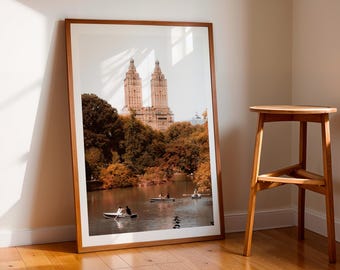 Peut inclure: Une photographie encadrée d'une ville avec deux grands bâtiments en arrière-plan. Les bâtiments sont entourés d'arbres et d'un lac avec des bateaux au premier plan. La photo est dans un cadre en bois et est accrochée à un mur blanc.