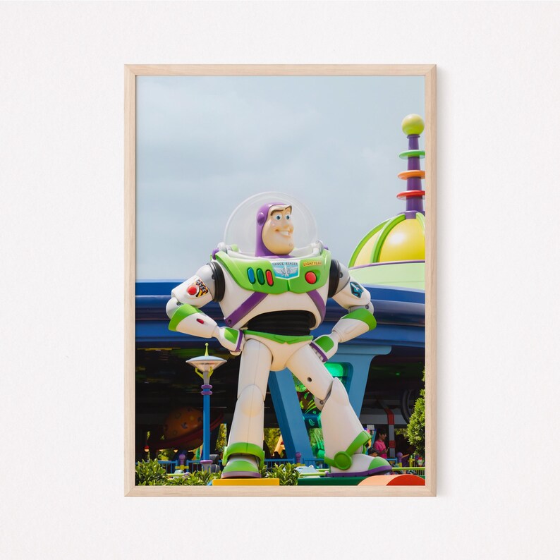 Puede incluir: Una gran estatua de pl&aacute;stico verde, blanco y morado de Buzz Lightyear de la franquicia Toy Story. La estatua est&aacute; de pie con los brazos en las caderas y mirando hacia la derecha. La estatua est&aacute; frente a un edificio azul y verde con una gran c&uacute;pula amarilla.