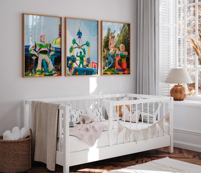 Puede incluir: Tres im&aacute;genes enmarcadas de personajes de Toy Story en un ambiente de guarder&iacute;a. Las im&aacute;genes son de Buzz Lightyear, Woody y un hombre verde del ej&eacute;rcito. Las im&aacute;genes est&aacute;n colgadas en una pared blanca sobre una cuna blanca con una manta blanca y una almohada a rayas blancas y negras.