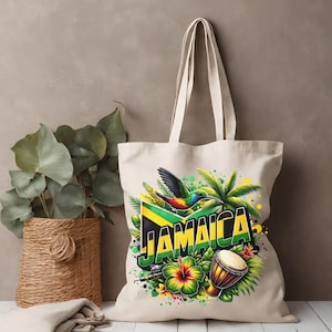 Puede incluir: Un bolso tote de lona natural con un diseño vibrante con la palabra "Jamaica" en amarillo y verde. El diseño incluye un colibrí, palmeras, un tambor y una flor de hibisco, todo sobre la bandera jamaicana.