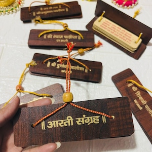 May include: A collection of wooden bookmarks and a small book with text. The bookmarks are rectangular, dark brown, and feature gold text and decorative cords. The text on the bookmarks includes phrases in a foreign language. The small book is open, revealing pages of text.
