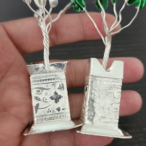 May include: Two silver miniature trees with green leaves in silver pots with intricate designs.