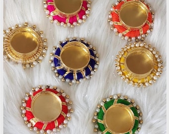 Puede incluir: Seis portavelas circulares para velas de té con centros de metal dorado envueltos en hilo de colores vibrantes, incluyendo rosa, naranja, amarillo, verde, azul y rojo. Cada portavelas tiene un borde de pequeñas cuentas blancas.
