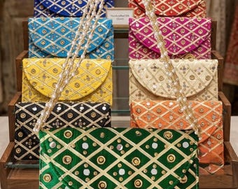 Puede incluir: Una colección de bolsos de mano rectangulares en varios colores, incluyendo verde, azul, amarillo, negro, rojo, rosa, crema y naranja. Cada bolso presenta un patrón de cuadrícula de diamantes con ribete dorado, espejos circulares y una correa de perlas.