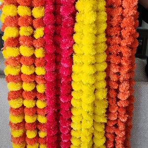 May include: A set of four garlands made of artificial marigold flowers. The garlands are in shades of orange, yellow, and pink.