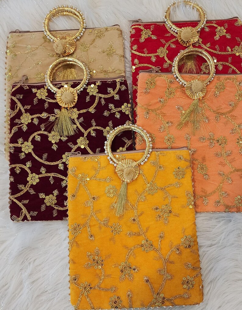 Puede incluir: Cinco bolsitas de terciopelo bordadas con ribetes dorados y asas de cuentas. Las bolsitas son de varios colores, incluyendo beige, rojo, granate, naranja y amarillo.