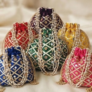 May include: A collection of six drawstring pouches in purple, red, blue, green, yellow, and pink. Each pouch features a gold lattice pattern with small circular mirrors and floral accents, finished with long, dangling white pearl bead straps.