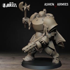May include: A detailed, tan-colored miniature figure of a heavily armored warrior, holding a large axe and a multi-barreled weapon. The figure is on a black base, with the text "Bite the Bullet" and "Ashen Armies" visible.