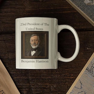May include: White ceramic mug with a black and white portrait of Benjamin Harrison, the 23rd President of the United States. The text "23rd President of The United States" and "Benjamin Harrison" are printed on the mug.