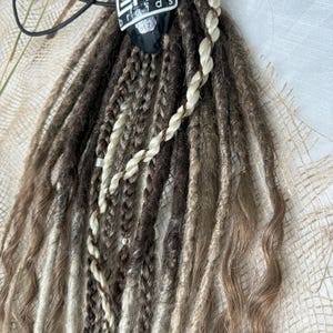 May include: A set of brown, blonde, and white synthetic dreadlocks with a black skull bead and a black and white "LORRI braids" label.